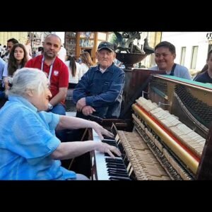 The grandmother sat in front of the piano on the street and played in such a way that people passing by gathered around her