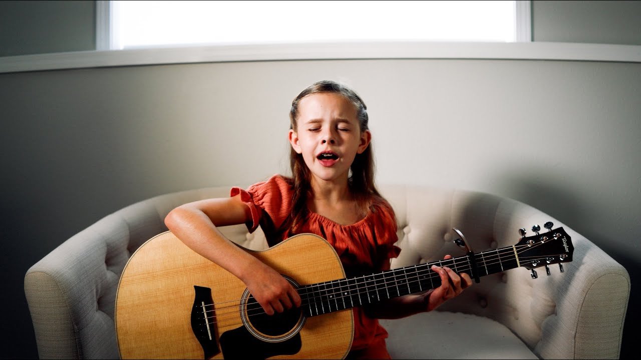 The little girl plays the guitar and sings a very beautiful song The little girl plays the guitar and sings a very beautiful song