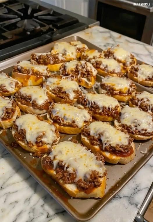 A plate of Texas Toast Sloppy Joes with thick, buttery toast slices piled high with saucy ground beef, served on a rustic wooden table with a side of pickles.