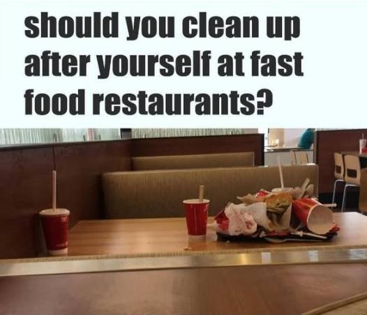 Customer carrying a tray to the trash bin in a fast food restaurant