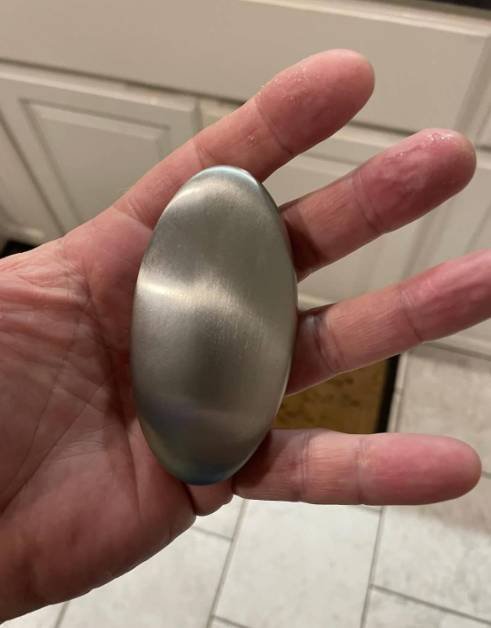 Stainless steel soap bar being used under running water to remove kitchen odors from hands